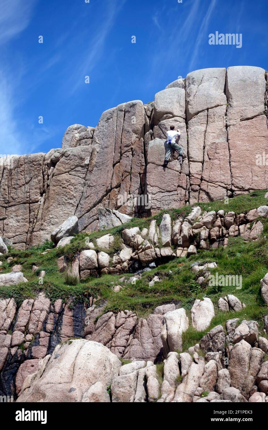 Man bouldering on the pink granite rocks at Balfour's Bay, Erraid, Isle of Mull, Scotland Stock Photo
