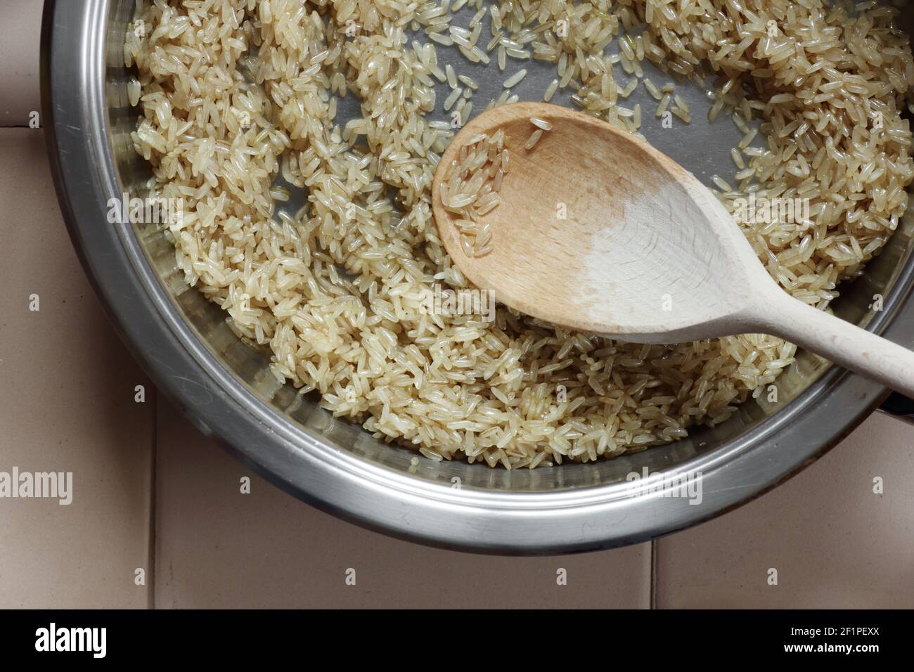Rice frying and oiling in ghee  on steel pan closeup, process of cooking asian indian basmati ghee rice dish with Stock Photo
