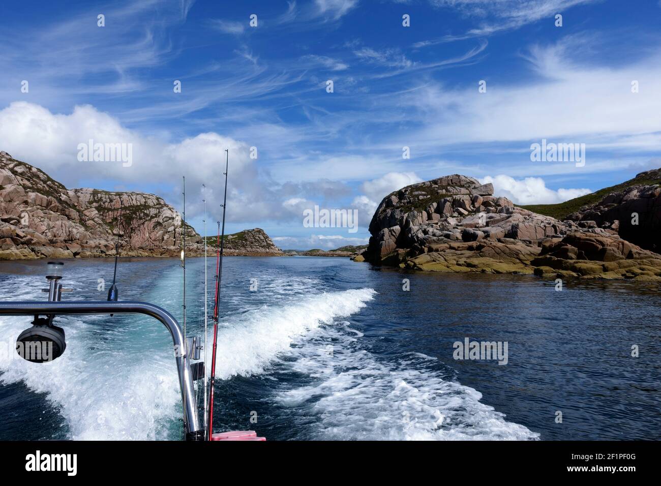 A rib going through Tinkers Hole with fishing rods strapped to the. Tinkers Hole is a sheltered mooring, off Erraid and the Isle of Mull in Scotland. Stock Photo