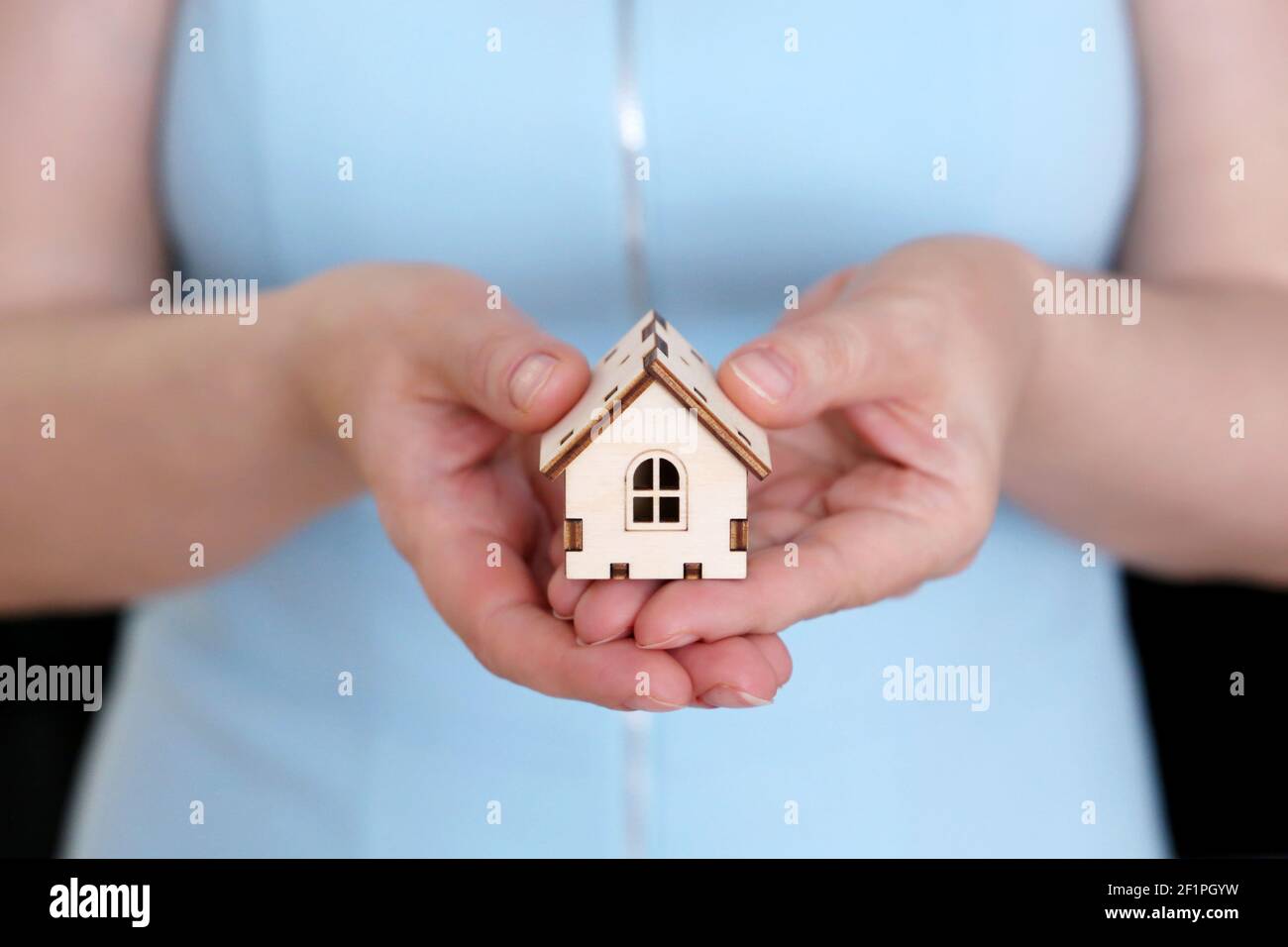 Real estate agent, wooden house in female hands. Woman with house model, purchase or rental home Stock Photo