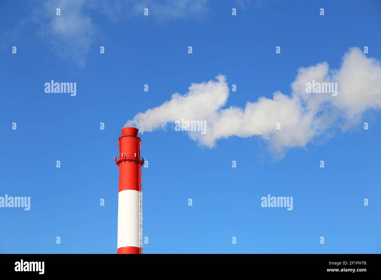 Factory chimney on blue sky background with white smoke. Concept of steam plant, air pollution, heating season Stock Photo