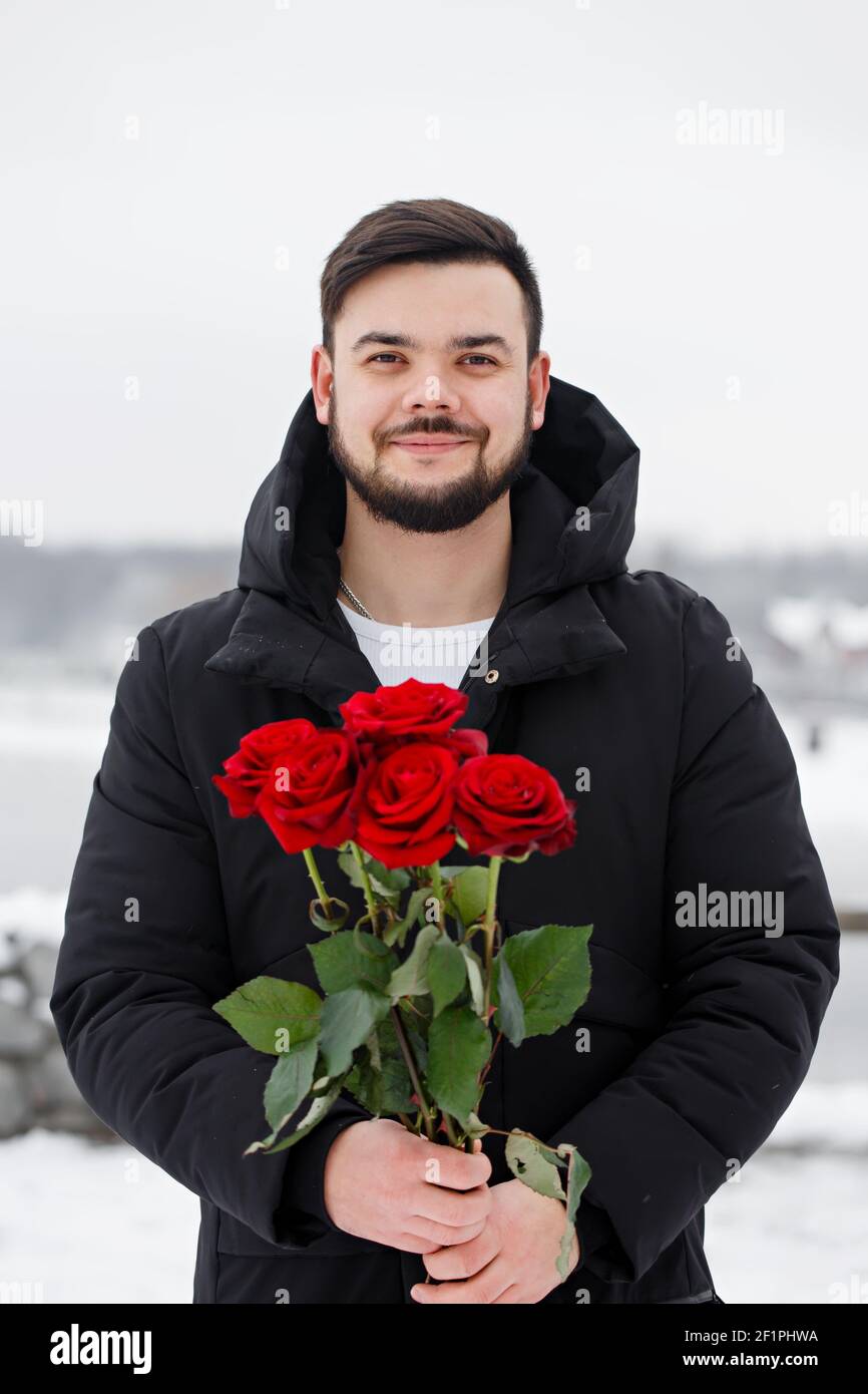 Handsome romantic young man with bouquet of red roses in hands Stock ...