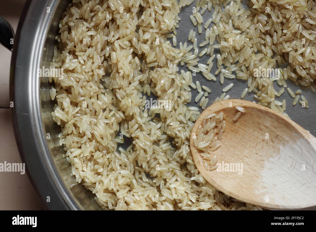 Rice frying and oiling in ghee  on steel pan closeup, process of cooking asian indian basmati ghee rice dish with Stock Photo