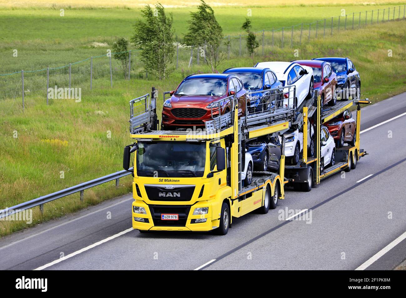 Yellow MAN TGS 26.460 car carrier of SE Makinen hauls new cars along freeway in the summer. Elevated view. Salo, Finland. July 10, 2020 Stock Photo