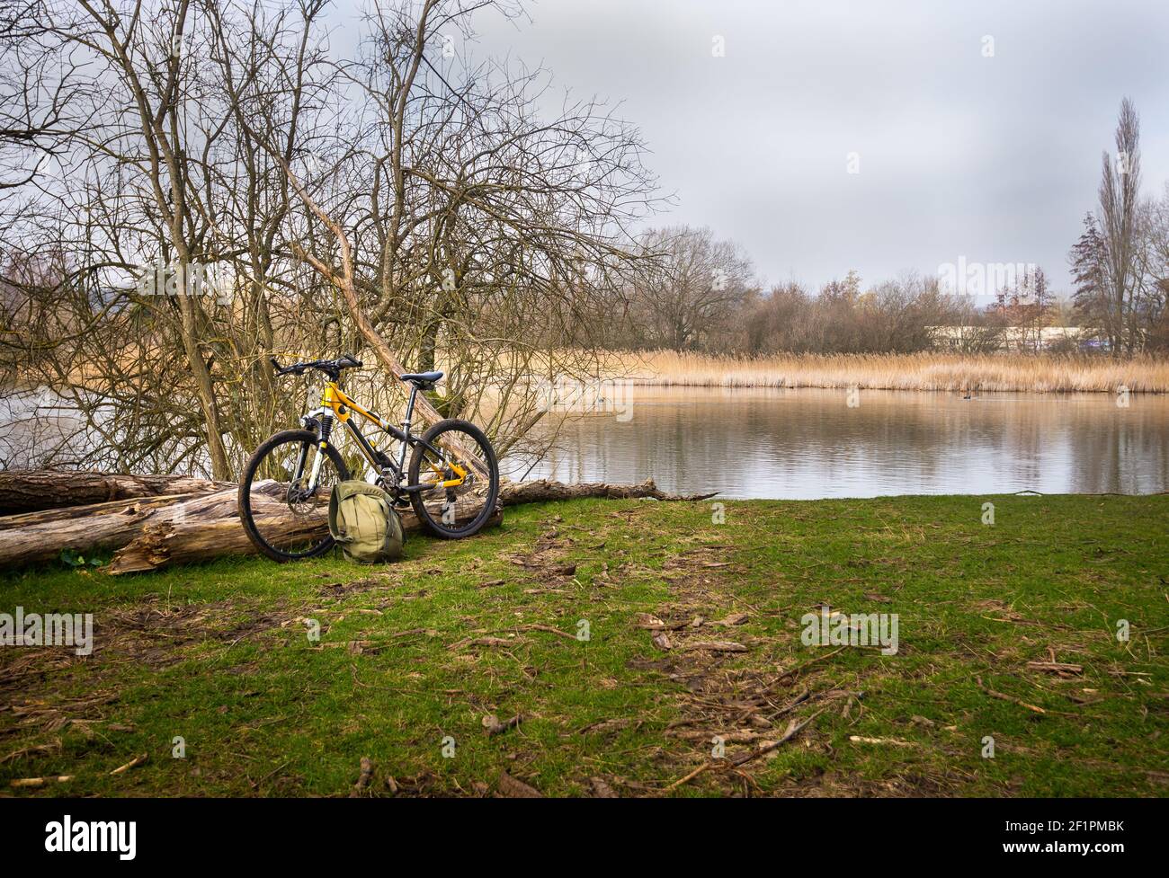 Bicycle and rug sack left beside lake on a bright winter day near Chartham in Kent. Stock Photo