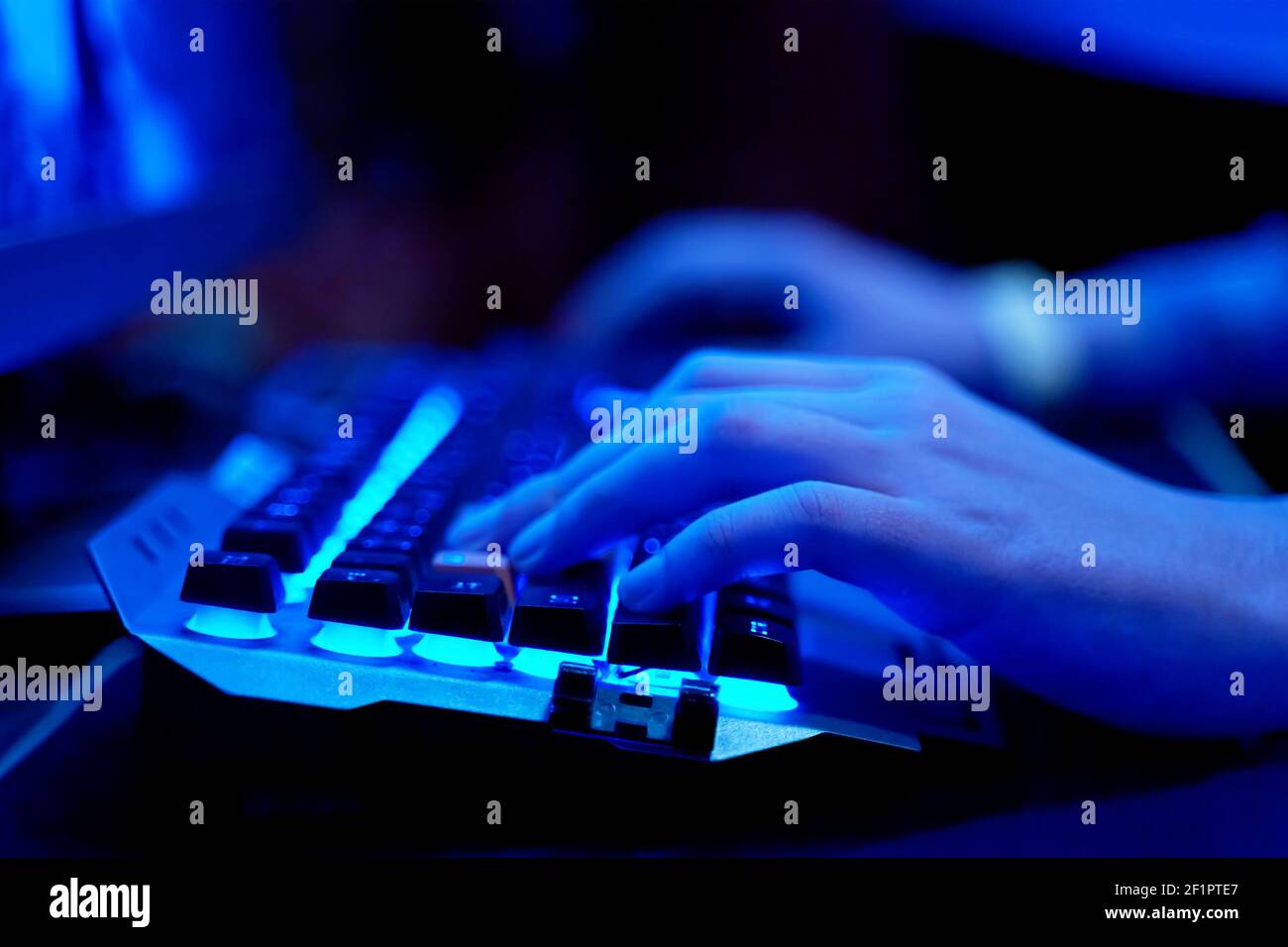 Gaming Keyboard. Closeup of hands on neon lit keyboard. Streaming online games on internet. Stock Photo
