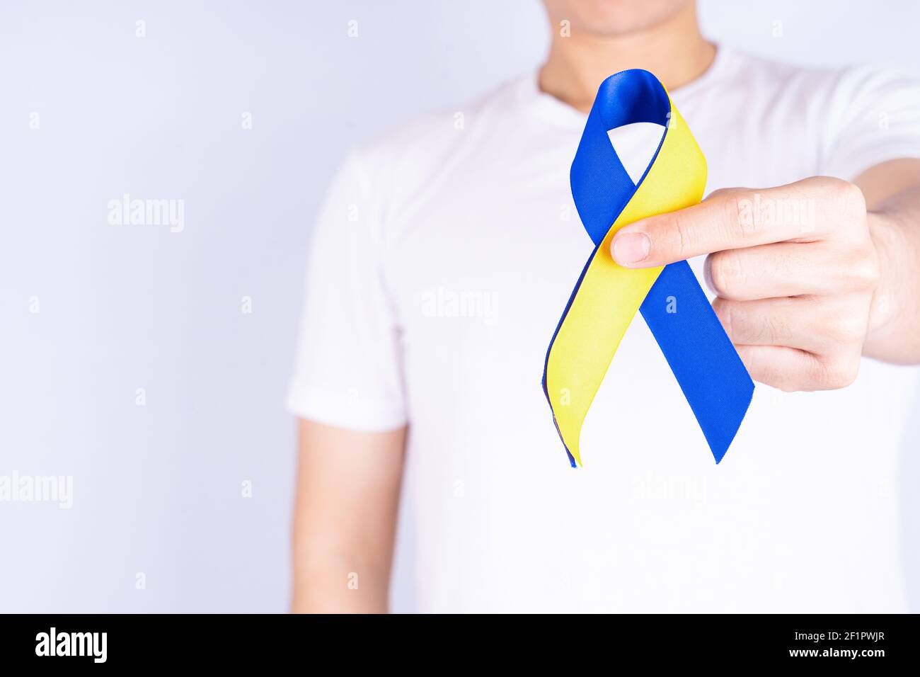 Down syndrome day, hands holding blue yellow ribbon awareness on chest ...