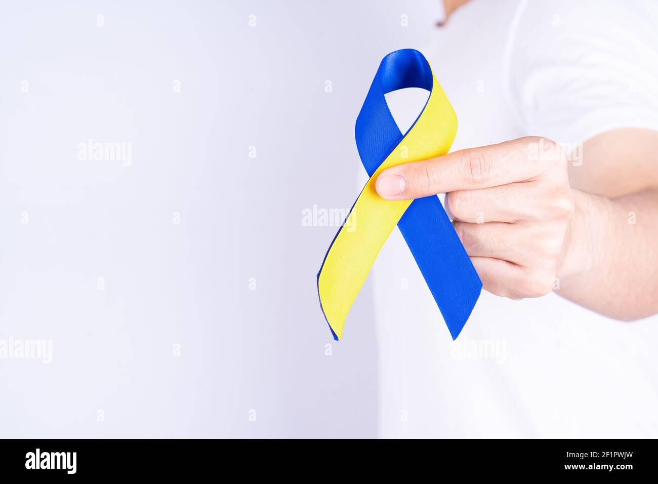 Down syndrome day, hands holding blue yellow ribbon awareness on chest ...