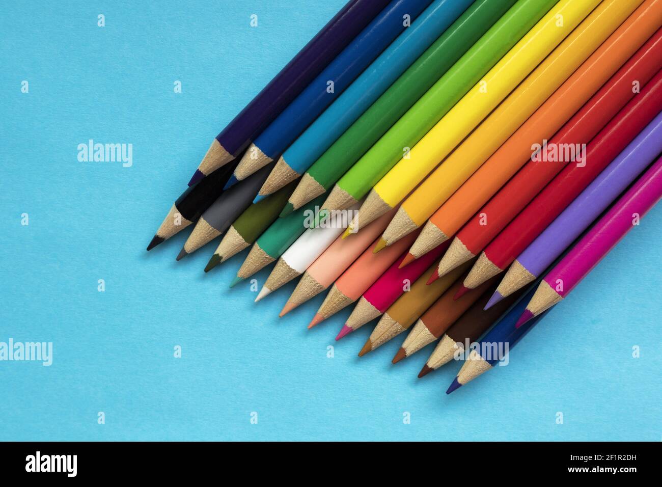 Multi colored pencils on blue paper background. Stock Photo