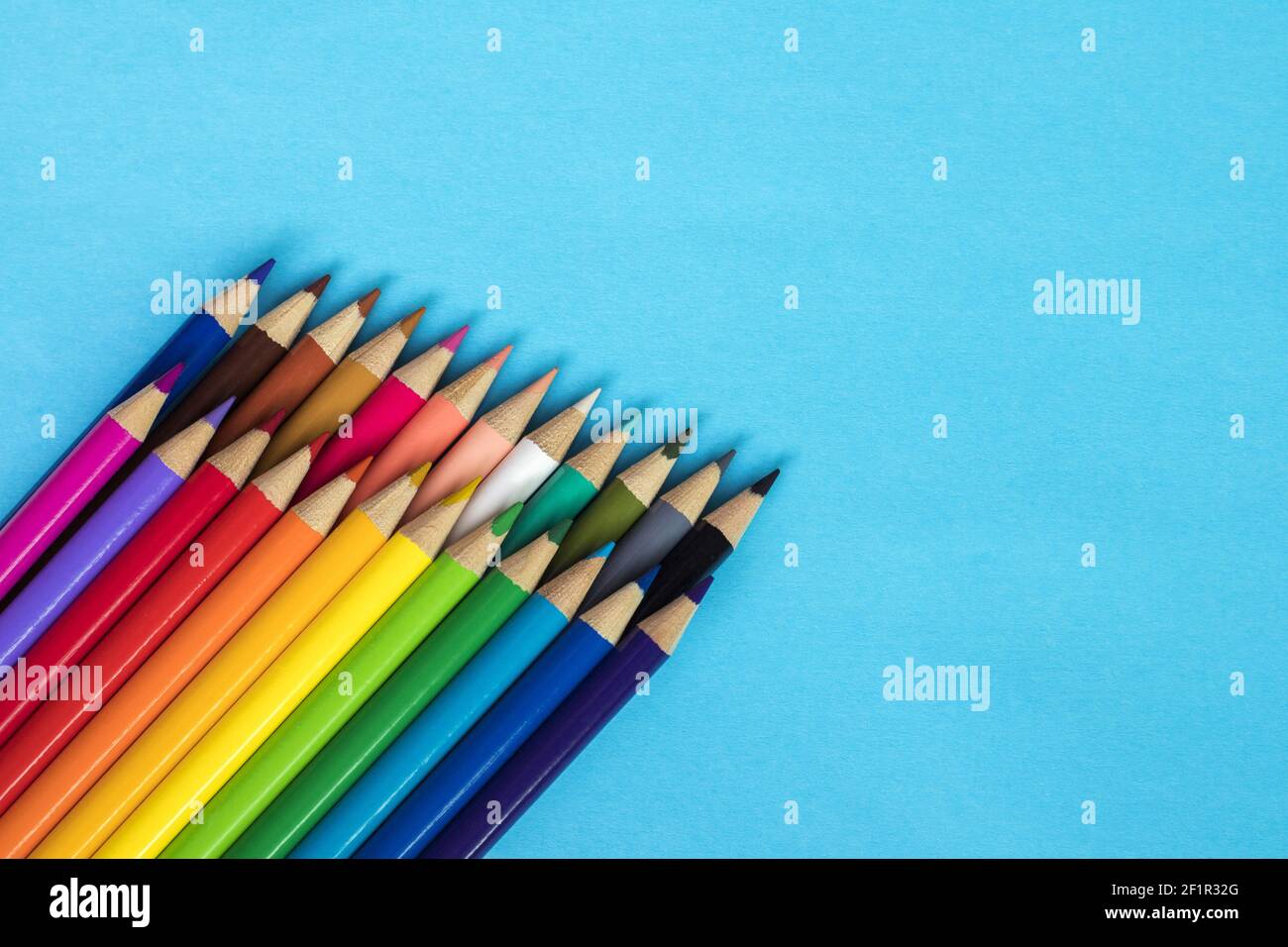 Multi colored pencils on blue paper background. Stock Photo