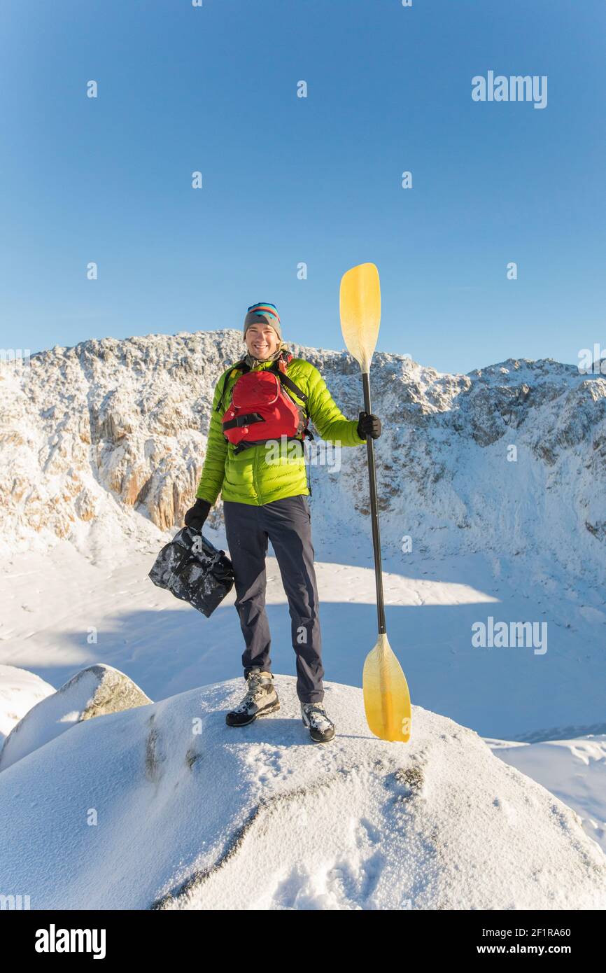 Paddler wearing life jacket holding paddle, boat sees frozen lake Stock Photo