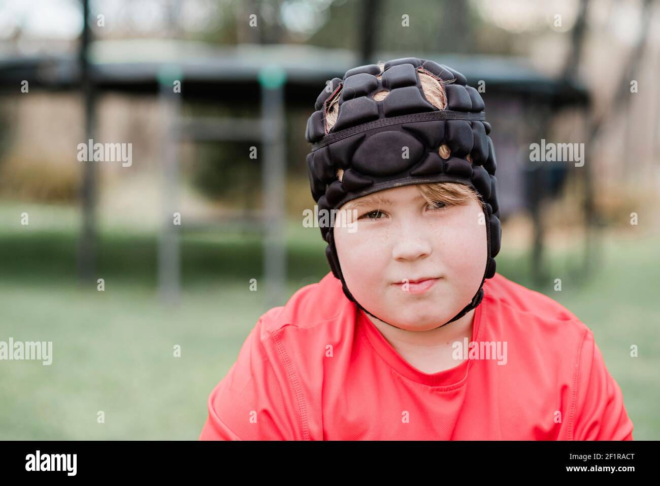 Young boy wearing protection head gear in back yard Stock Photo