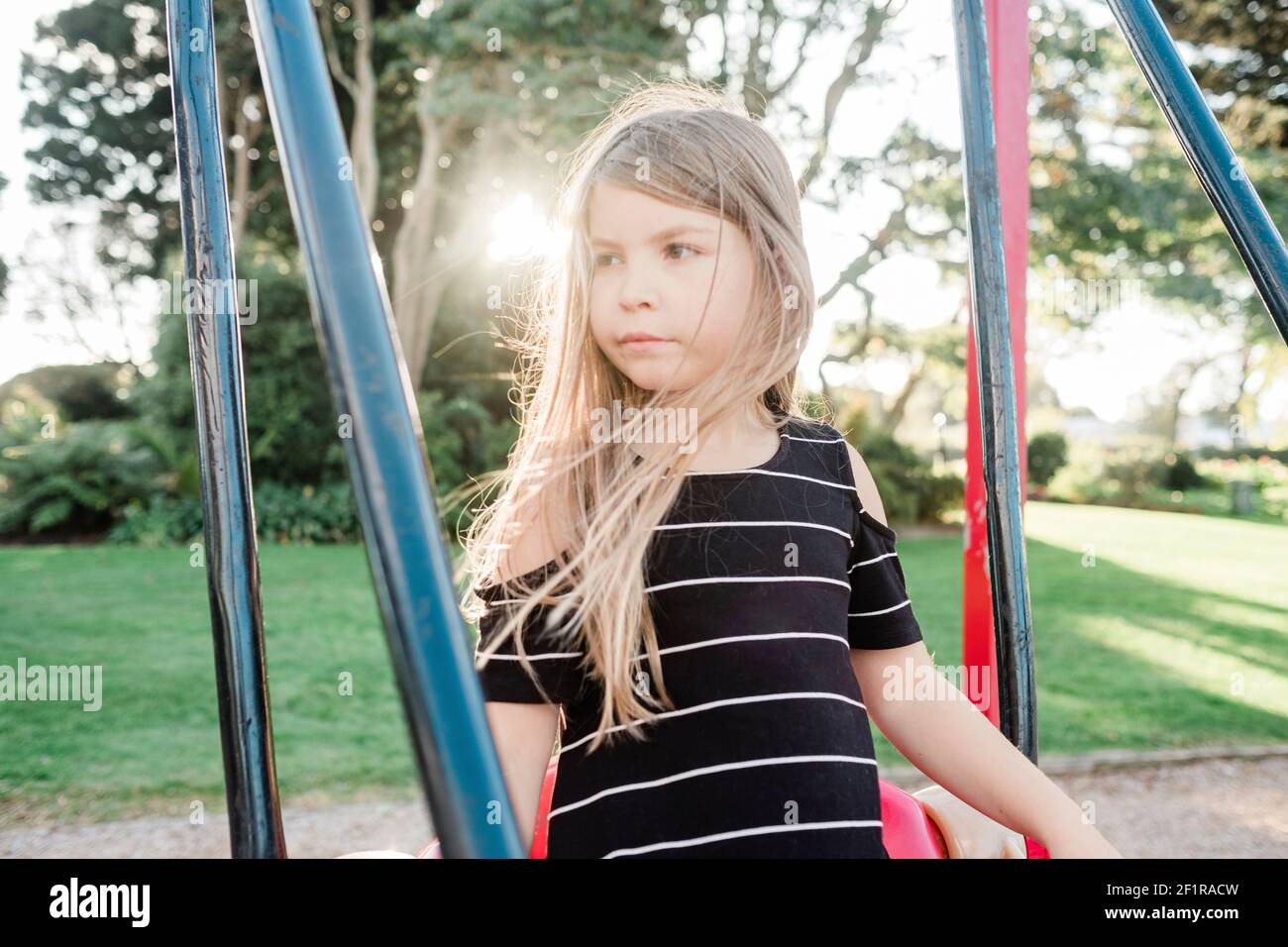 Young girl standing on a swing at a public playground Stock Photo