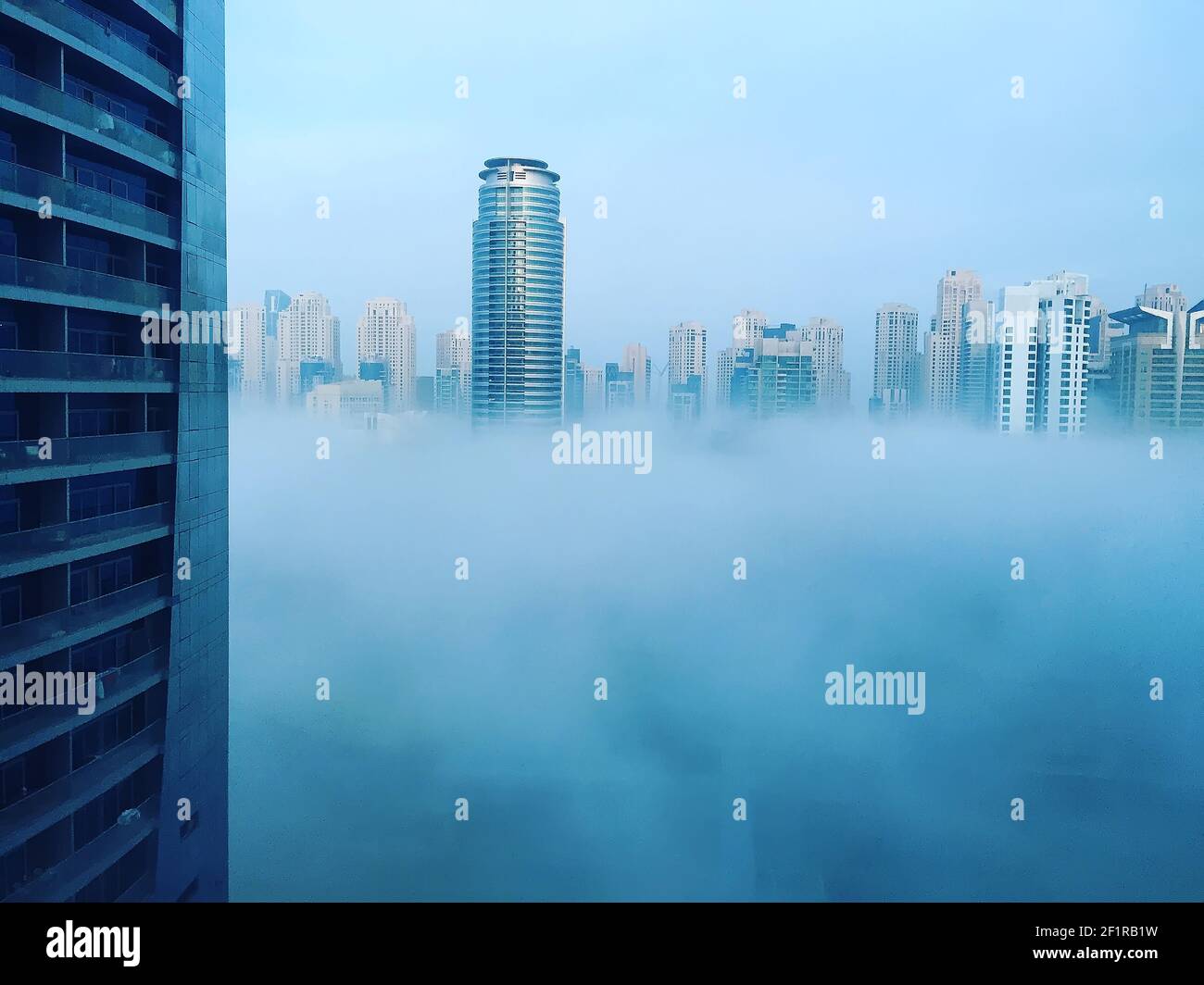 Modern skyscrapers of Dubai Marina in blue fog, climate change Stock Photo