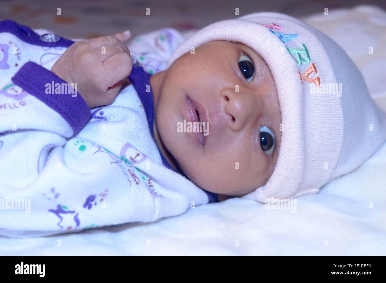 Close up portrait of a cute newborn baby boy lying bed and looking ...