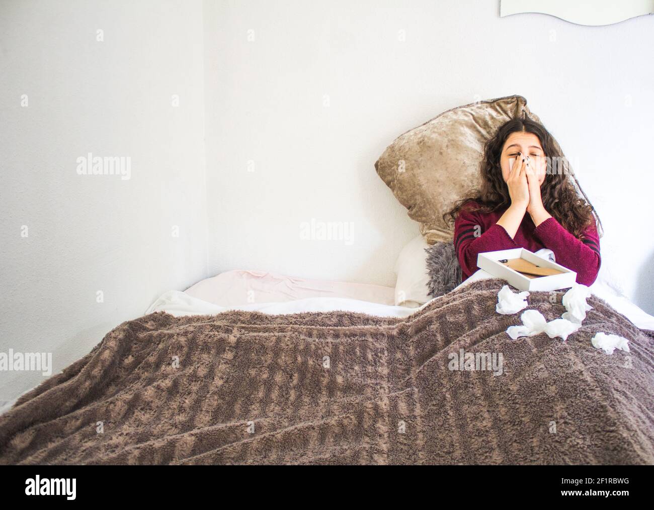 young woman lying crying with photograph and handkerchiefs in bed Stock Photo