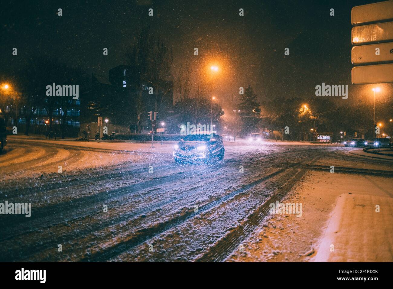 Cars driving carefully in snow covered roads during Filomena snowstorm in Madrid, Spain. Stock Photo