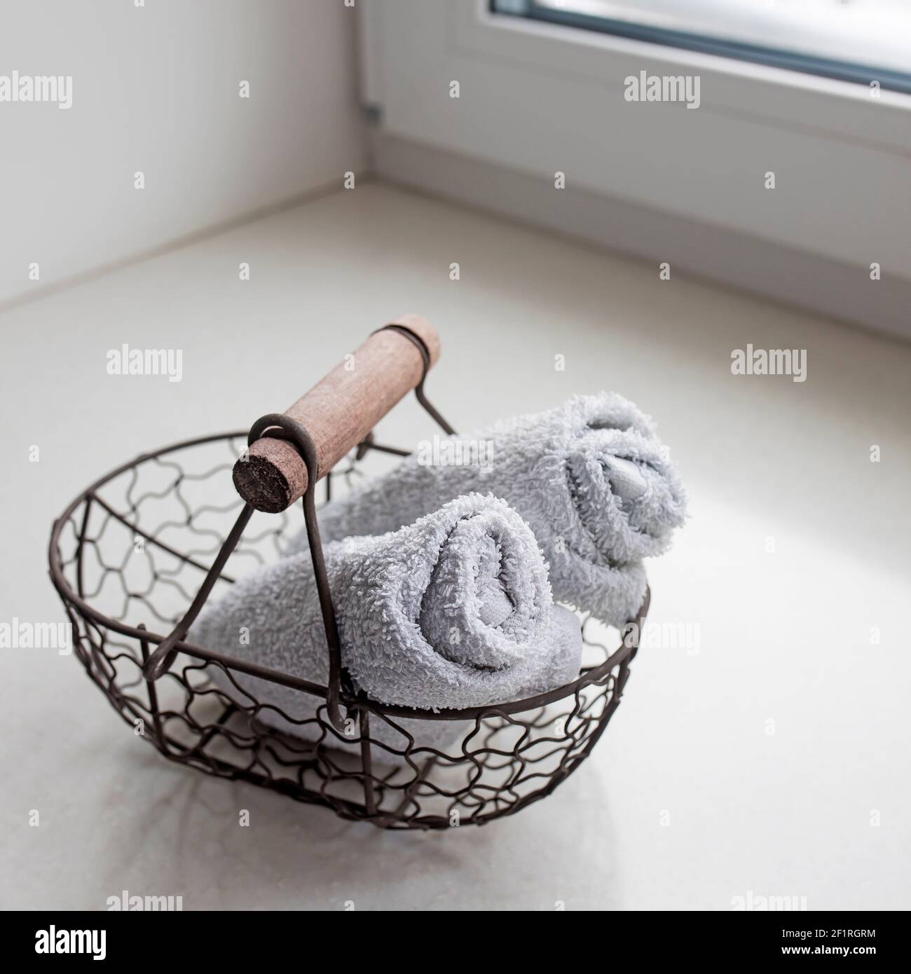 rolled towels in metal basket at clean bathroom. Square frame Stock