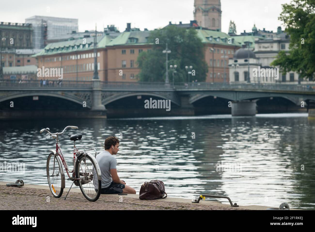 A man sits with his bike on Stadshuskajen, Stockholm, Sweden. Stock Photo