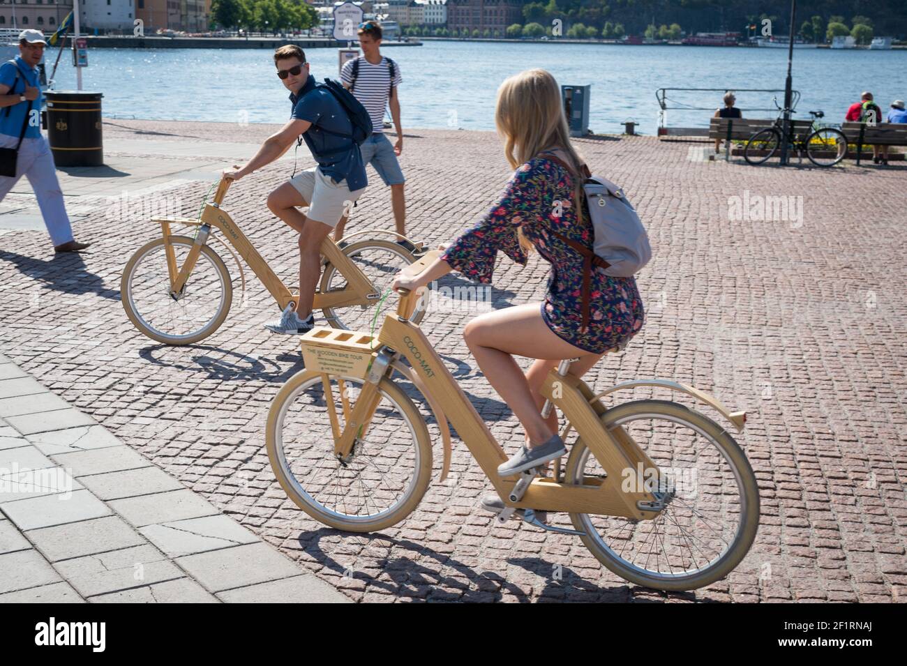 A young couple ride wooden bikes on Stadshuskajen, Stockholm, Sweden. Stock Photo