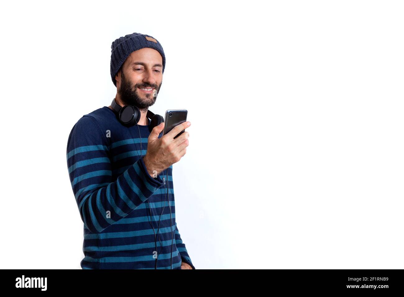 Man with headphones looking his cell smartphone. White background. Stock Photo