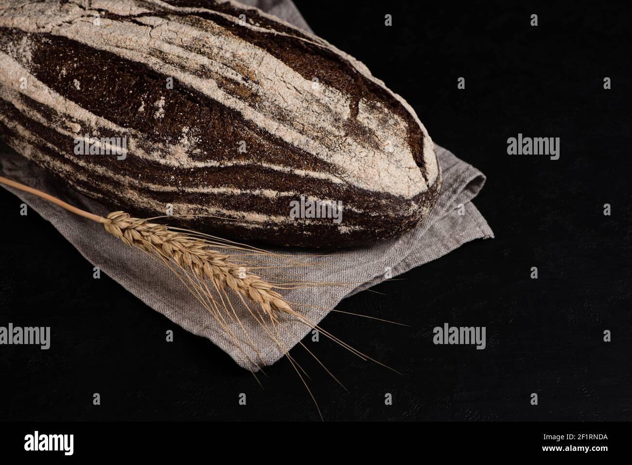 Rustic dark rye bread on black background. Freshly baked sourdough