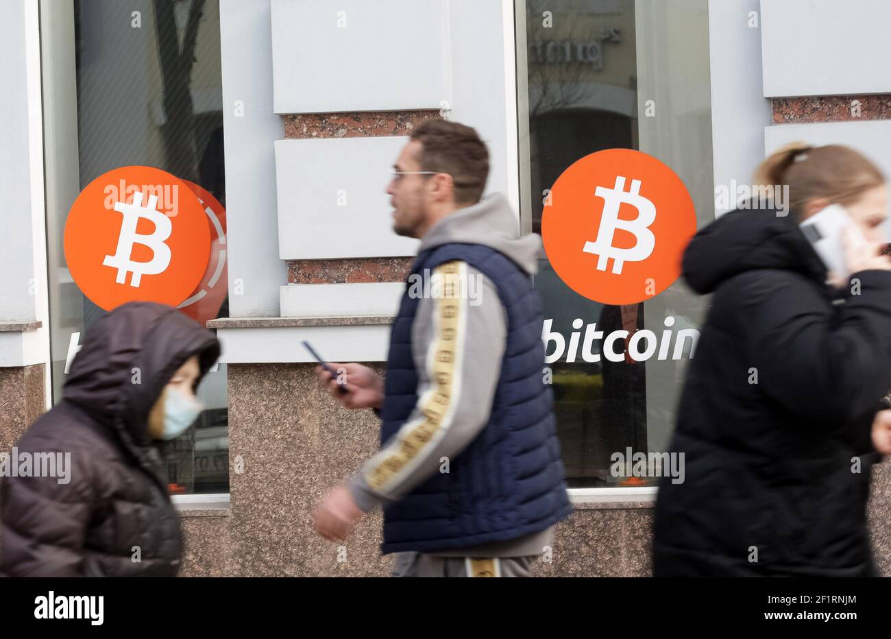 People walk past an office of Bitcoin (BTC) cryptocurrency exchange.Over  the past day, the price of Bitcoin cryptocurrency increased by 7.46% and  reached $ 54,310, Bitcoin quotes have recovered their growth, and