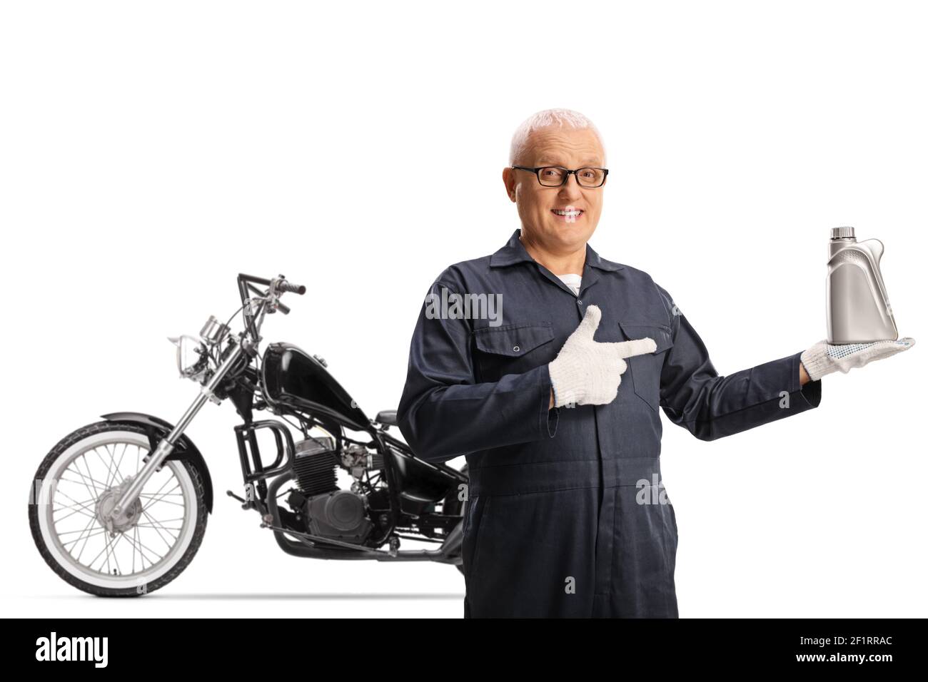 Motorbike mechanic holding an engine oil and posing in front of a chopper isolated on white background Stock Photo