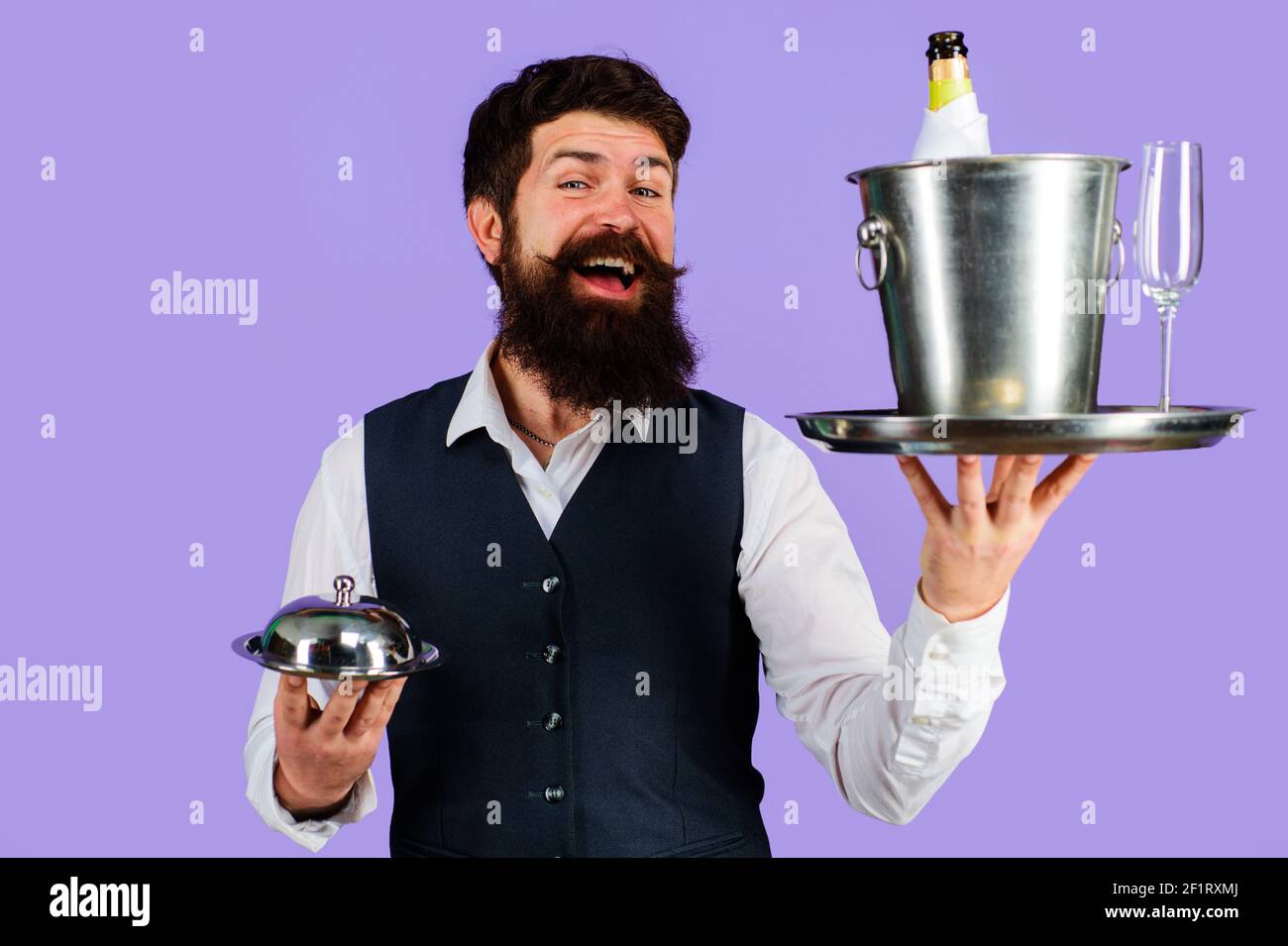 Restaurant serving. Waiter with serving tray with wine cooler and metal cloche. Stock Photo