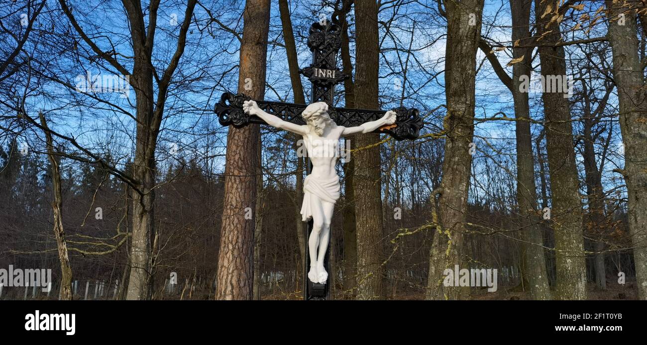 Cross and Jesus Christ statue on forest background. Religious symbol. Catholicism and Christianity.Monuments and statues in Europe. Cemetery and Stock Photo