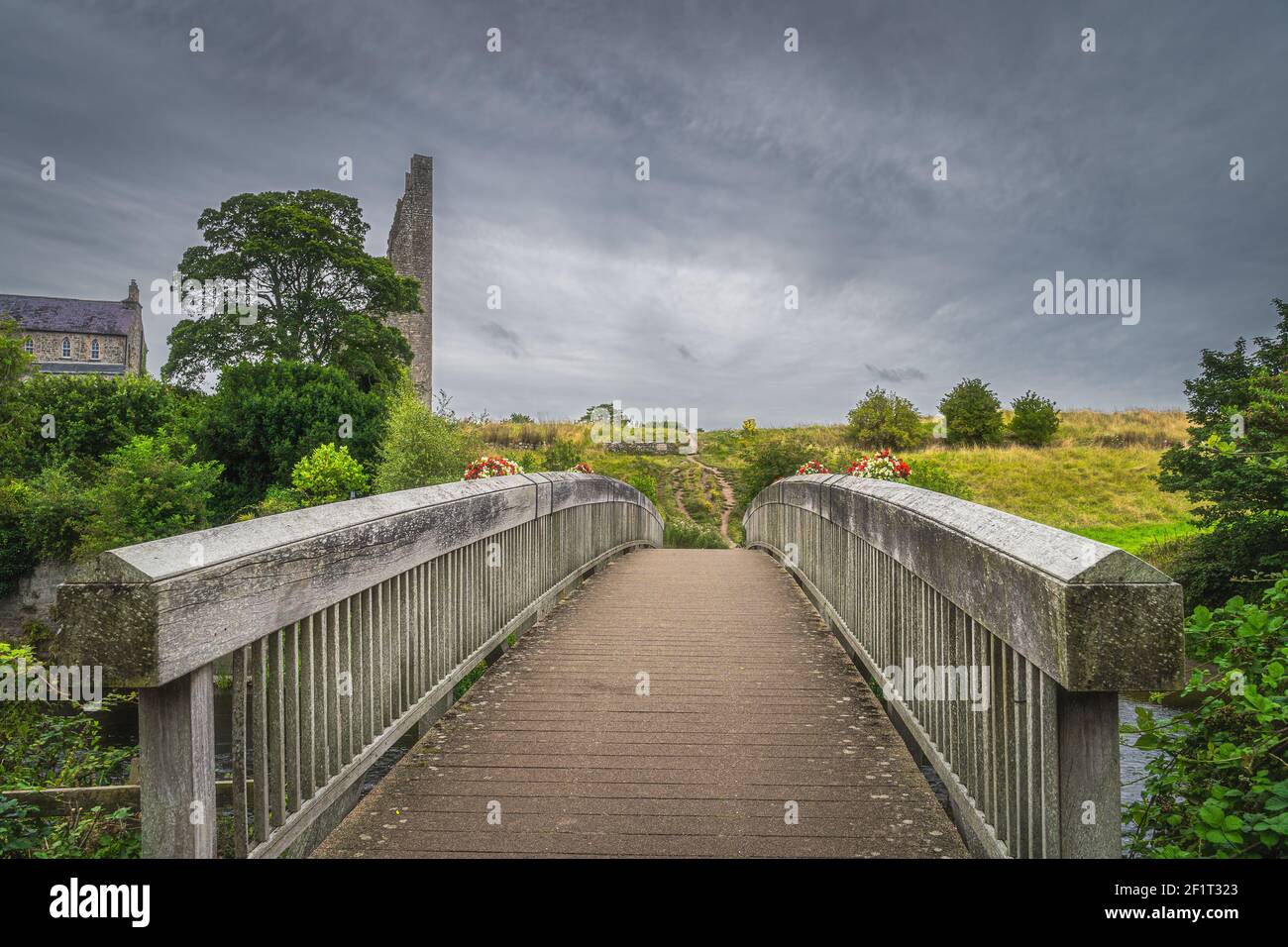 Wooden bridge over River Boyne with a view on ruined tower of St. Marys