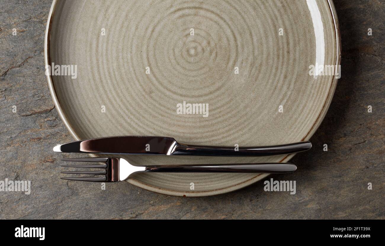Plate, knife and fork on stone background Stock Photo