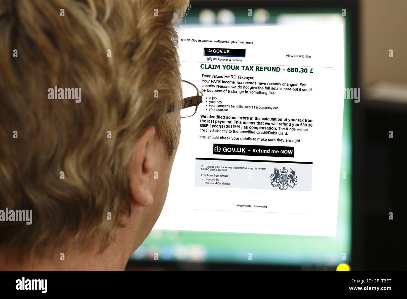 A woman reading a phishing email claiming that she is entitled to a tax refund. (UK). Editorial only Stock Photo