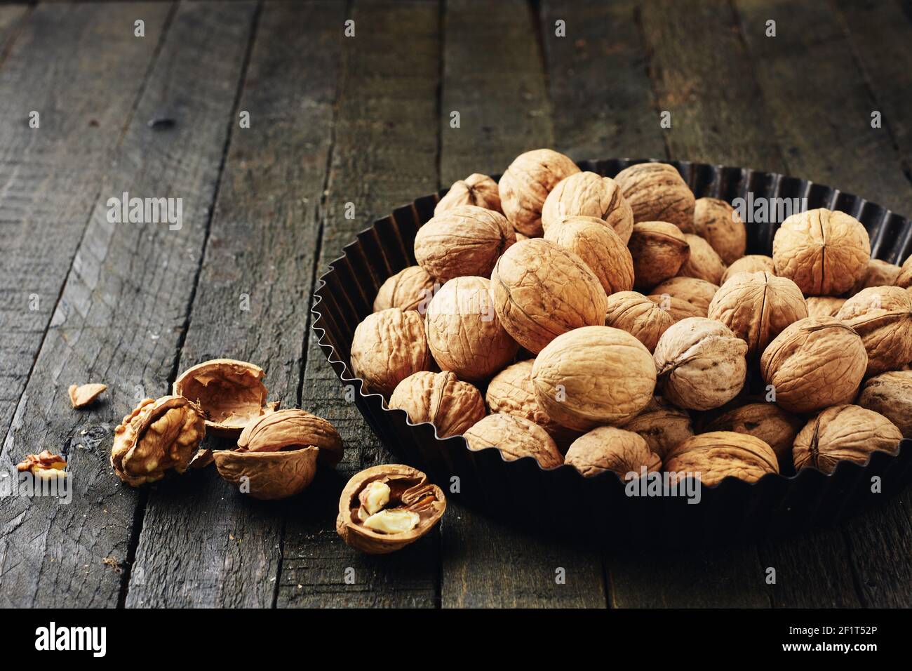 Whole walnuts and kernels on a dark wooden table. Stock Photo