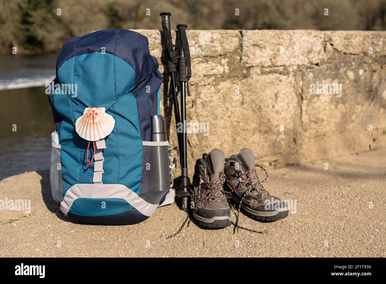 Backpack with seashell symbol of Camino de Santiago, trekking boots and  poles leaning on stone wall. Pilgrimage to Santiago de Compostela. Copy  space Stock Photo - Alamy