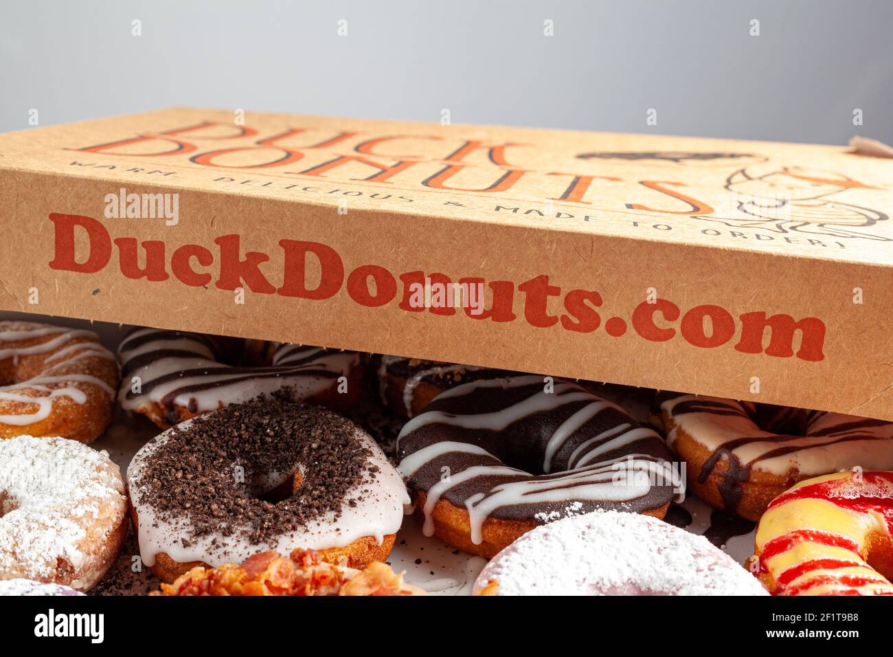 Clarksburg, MD, USA 03-04-2021: A cardboard box of a dozen donuts bought from the chain store Duck Donuts. A popular selection of assorted donuts are Stock Photo