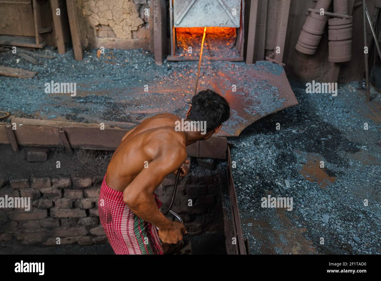 A rolling mill worker seen working in the steel re-rolling mill without proper safety gear or tools in Dhaka, Bangladesh on March 9, 2021. Stock Photo