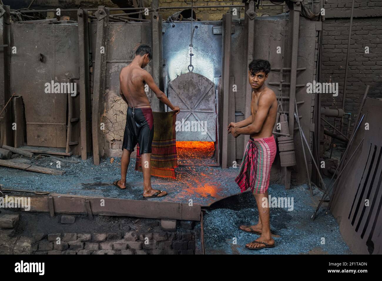 A rolling mill worker seen working in the steel re-rolling mill without proper safety gear or tools in Dhaka, Bangladesh on March 9, 2021. Stock Photo