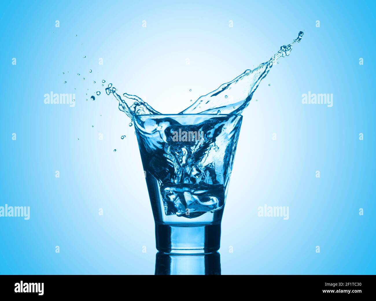 Water with splash and ice on blue background. Mineral water with ice in ...