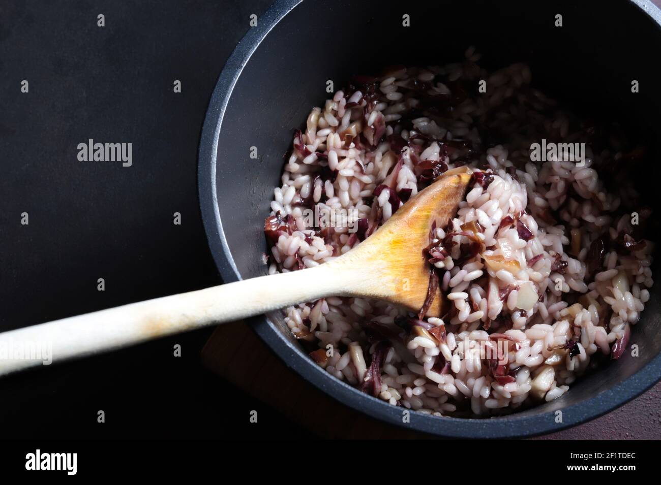 Italian risotto with red radicchio in a pan  on dark background. Venetian cuisine, Italy. View from above. Stock Photo