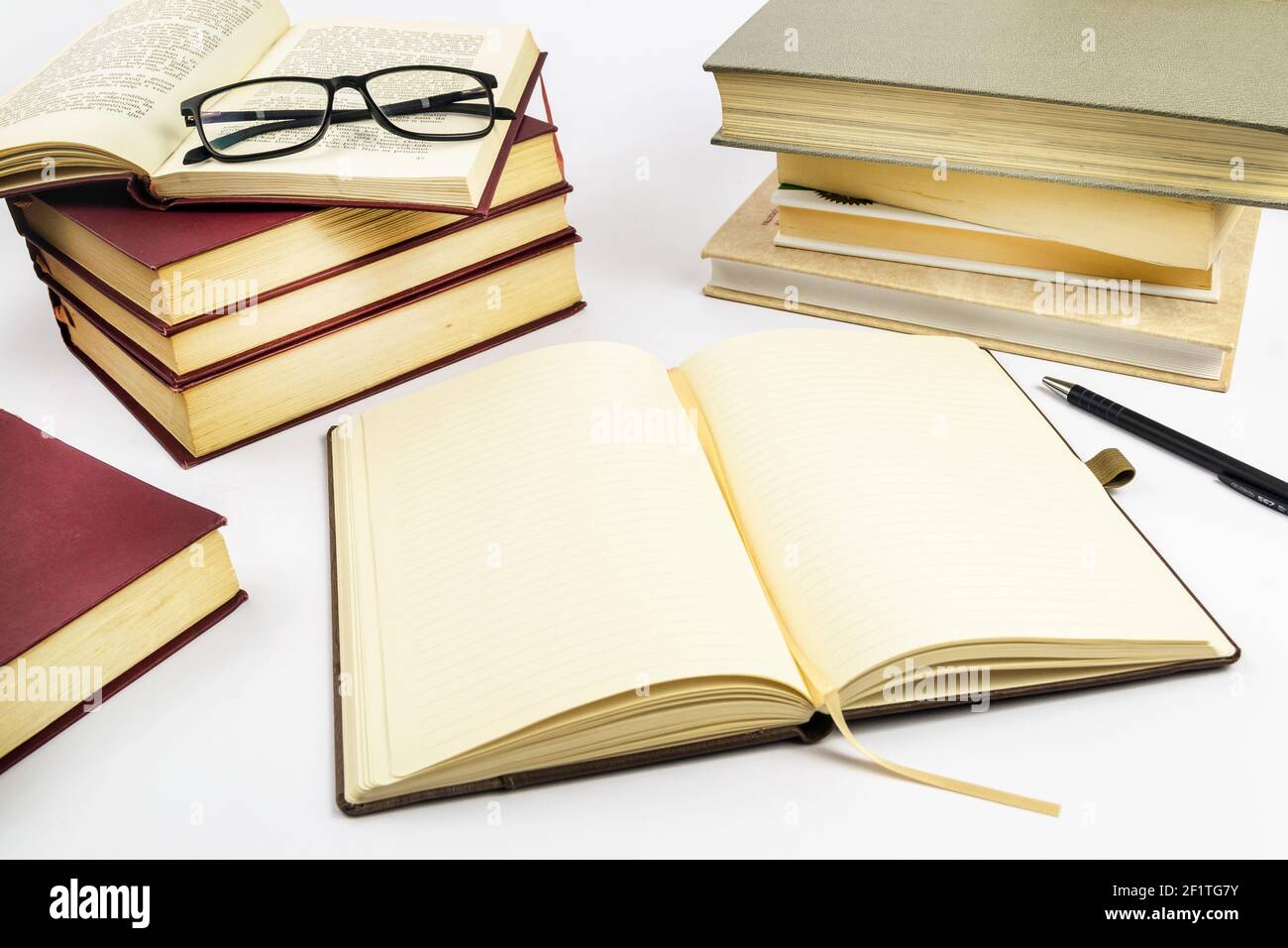 Open notebook with stack of books in background. Selective focus. Stock Photo