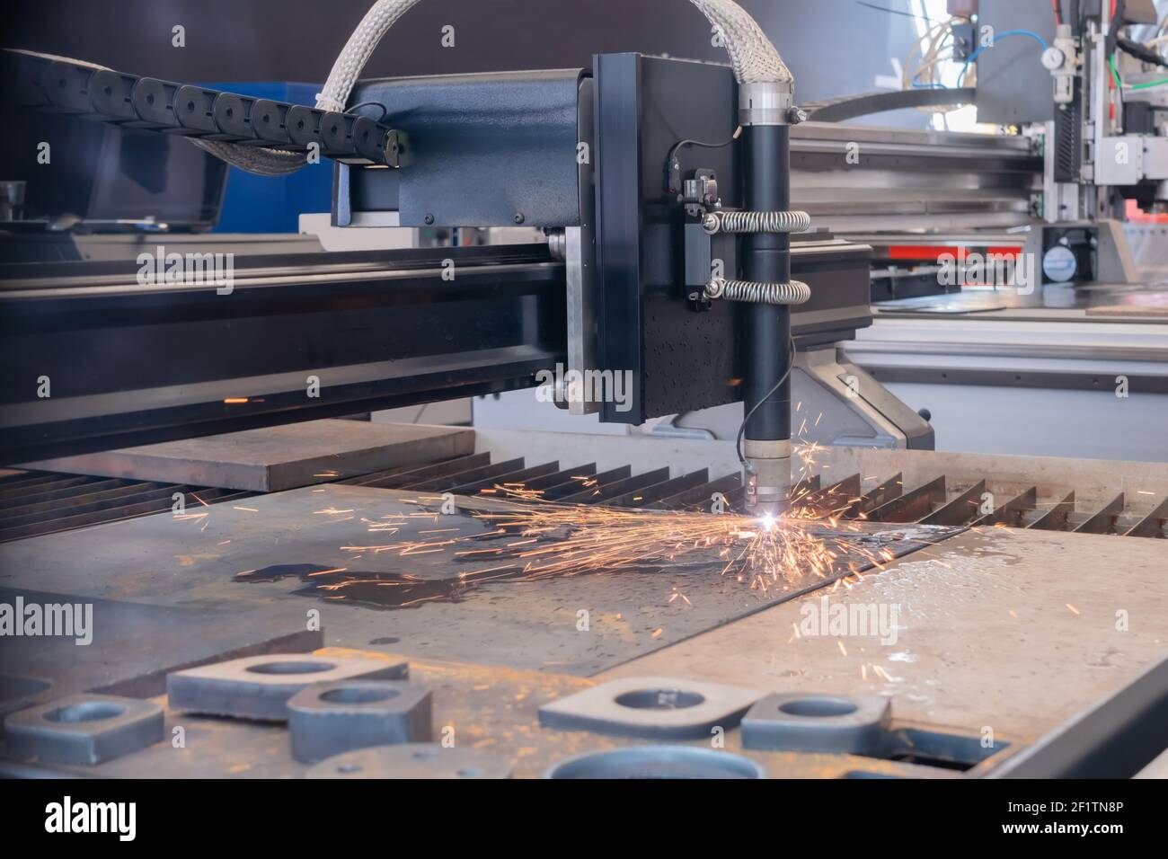 Plasma cutting machine working with sheet metal with sparks at
