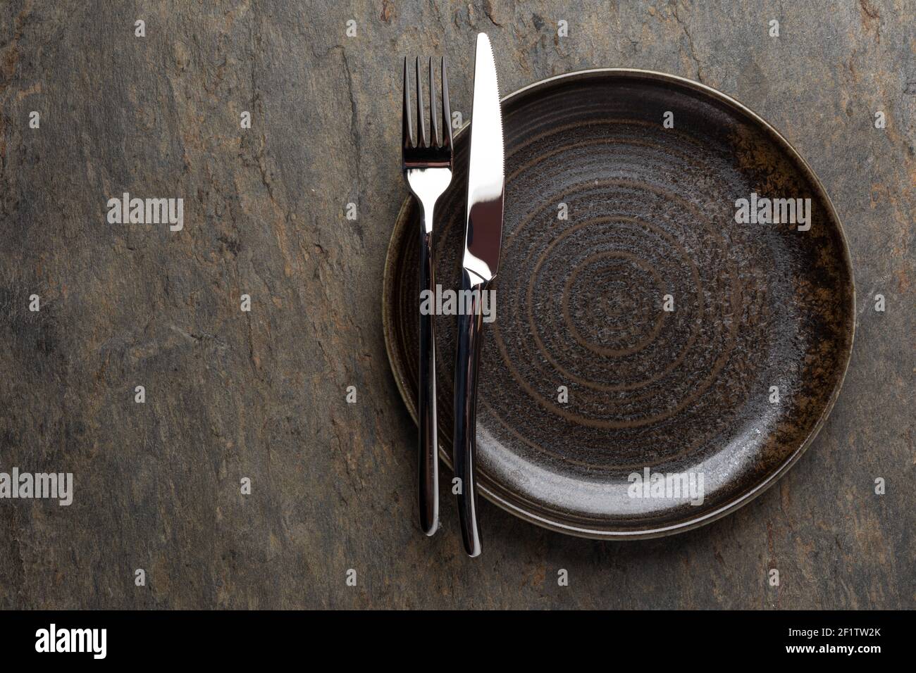 Plate, knife and fork on stone background Stock Photo