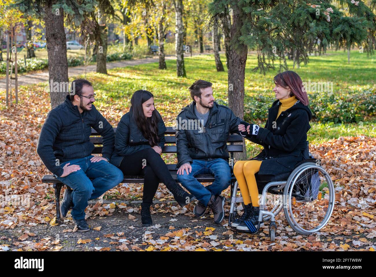 Young disabled woman in a wheelchair with friends in a park Stock Photo