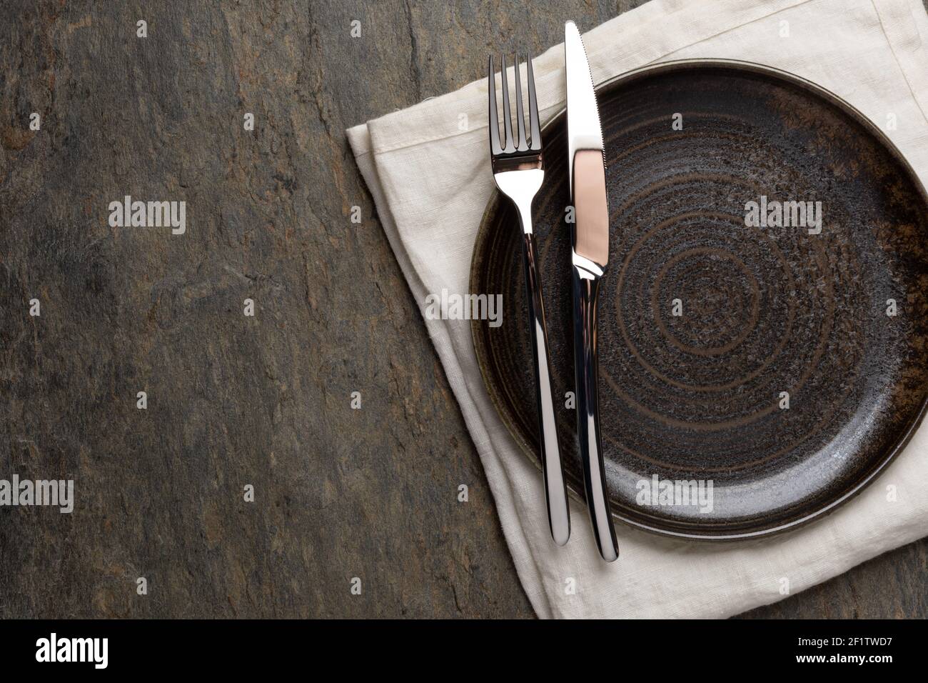 Plate, knife and fork on stone background Stock Photo