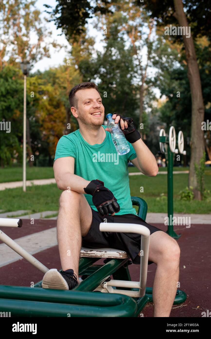 Refreshment during a training in outdoor gym on exercise equipment Stock Photo