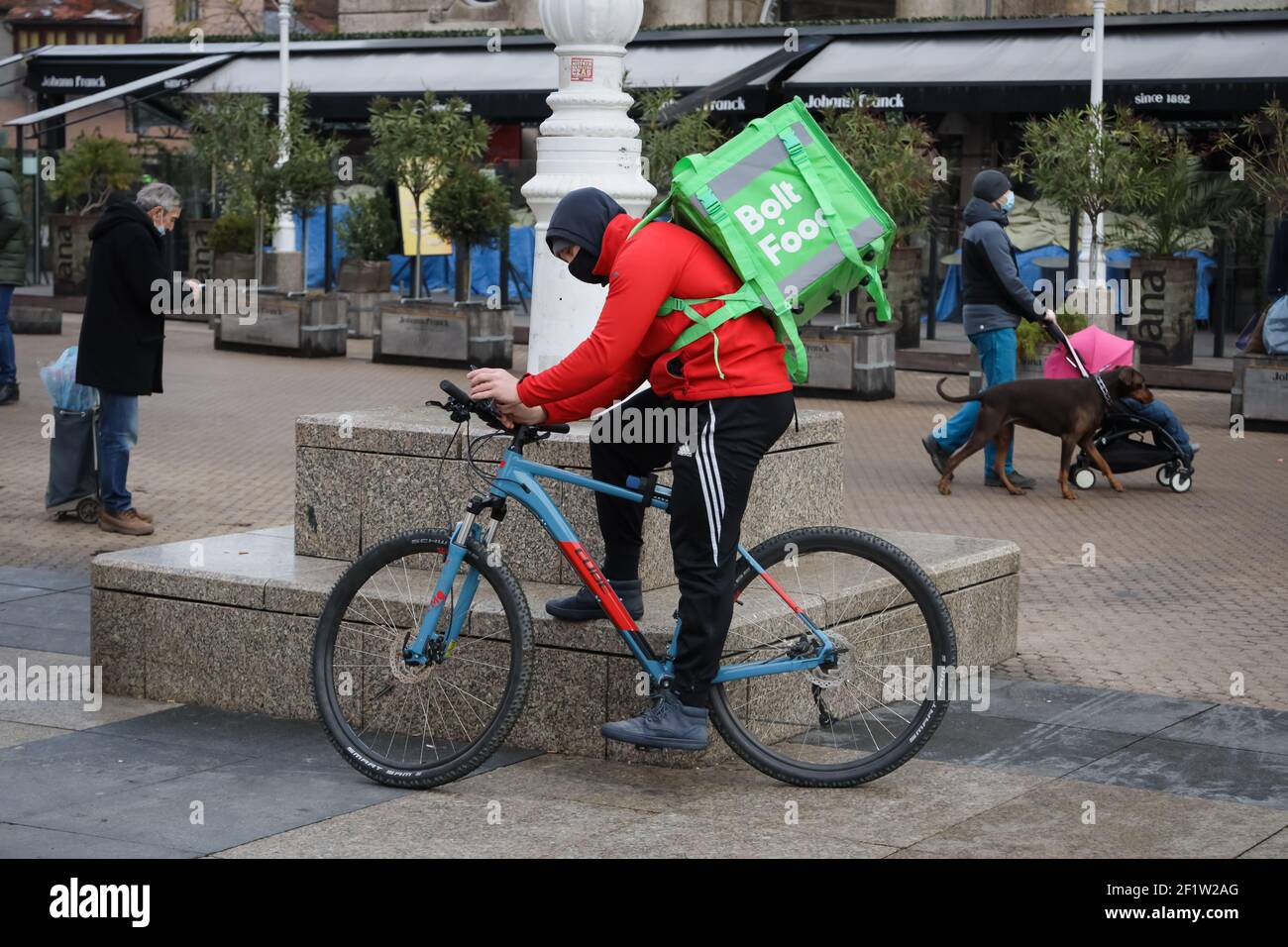 A Bolt Food delivery man on a bicycle is waiting for an order to deliver food from the restaurant. Stock Photo