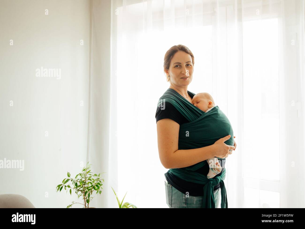 Happy mother with sleeping newborn in baby carrier Stock Photo Alamy
