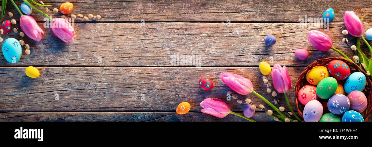 Easter Decoration - Painted Eggs In Vintage Basket On Rustic Table With Willows Branches And Tulips Stock Photo