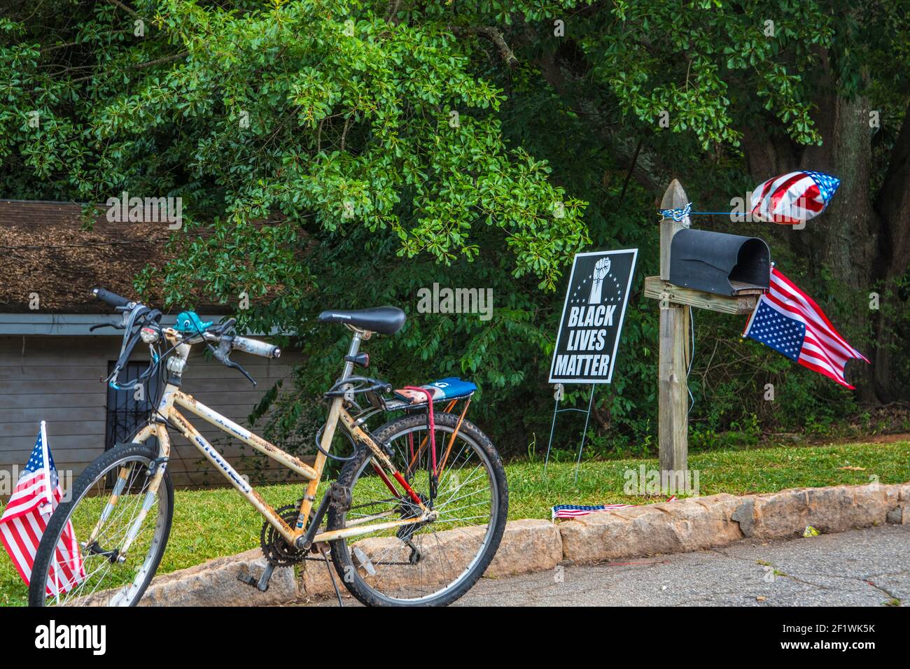 Doraville, Ga / USA - 07 06 20: Black Lives Matter yard sign, a bicycle and an American flag Stock Photo